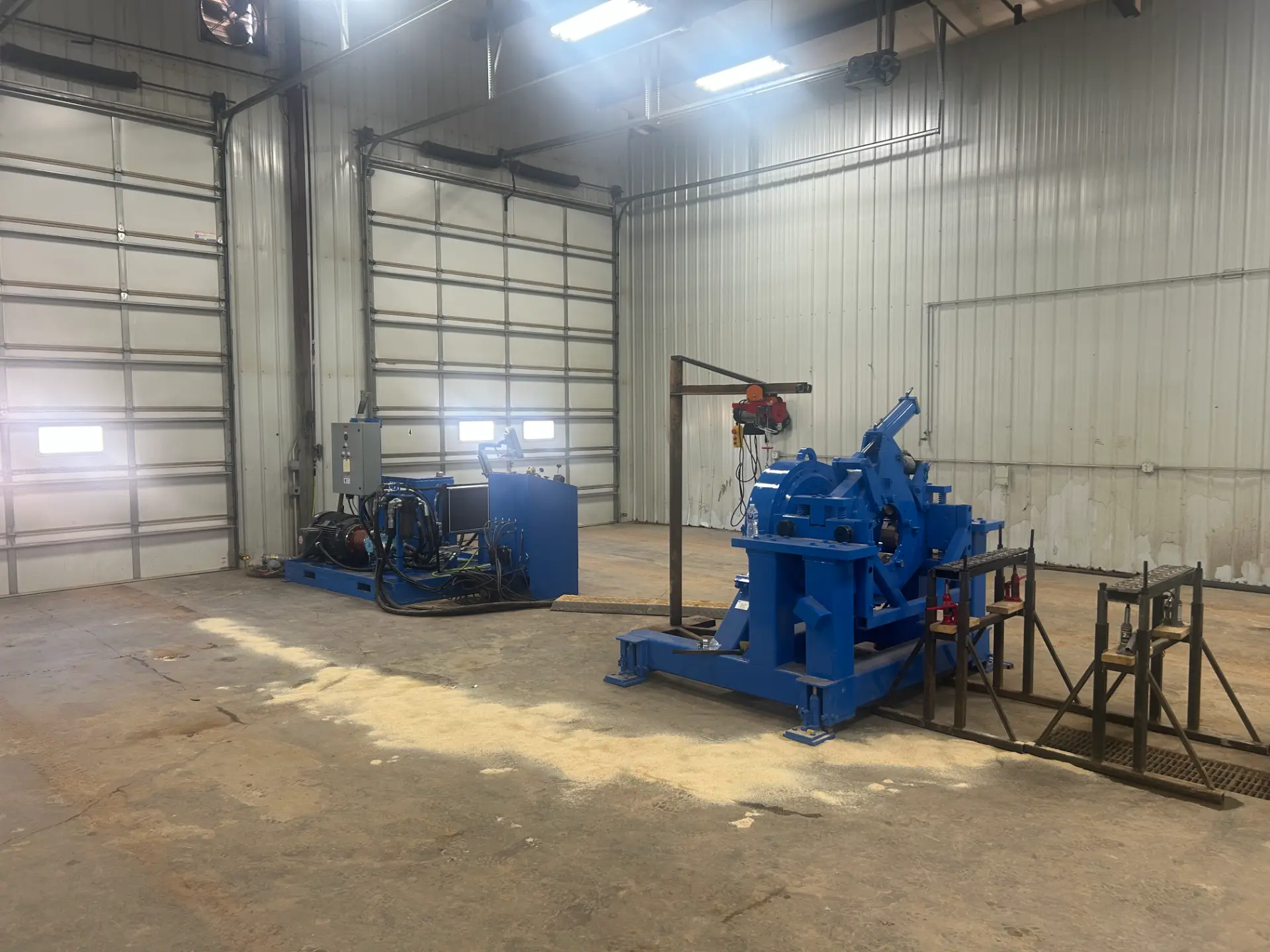 Wide view of the WOS bucking unit power pack and bucking head with pipe stands in the shop bay