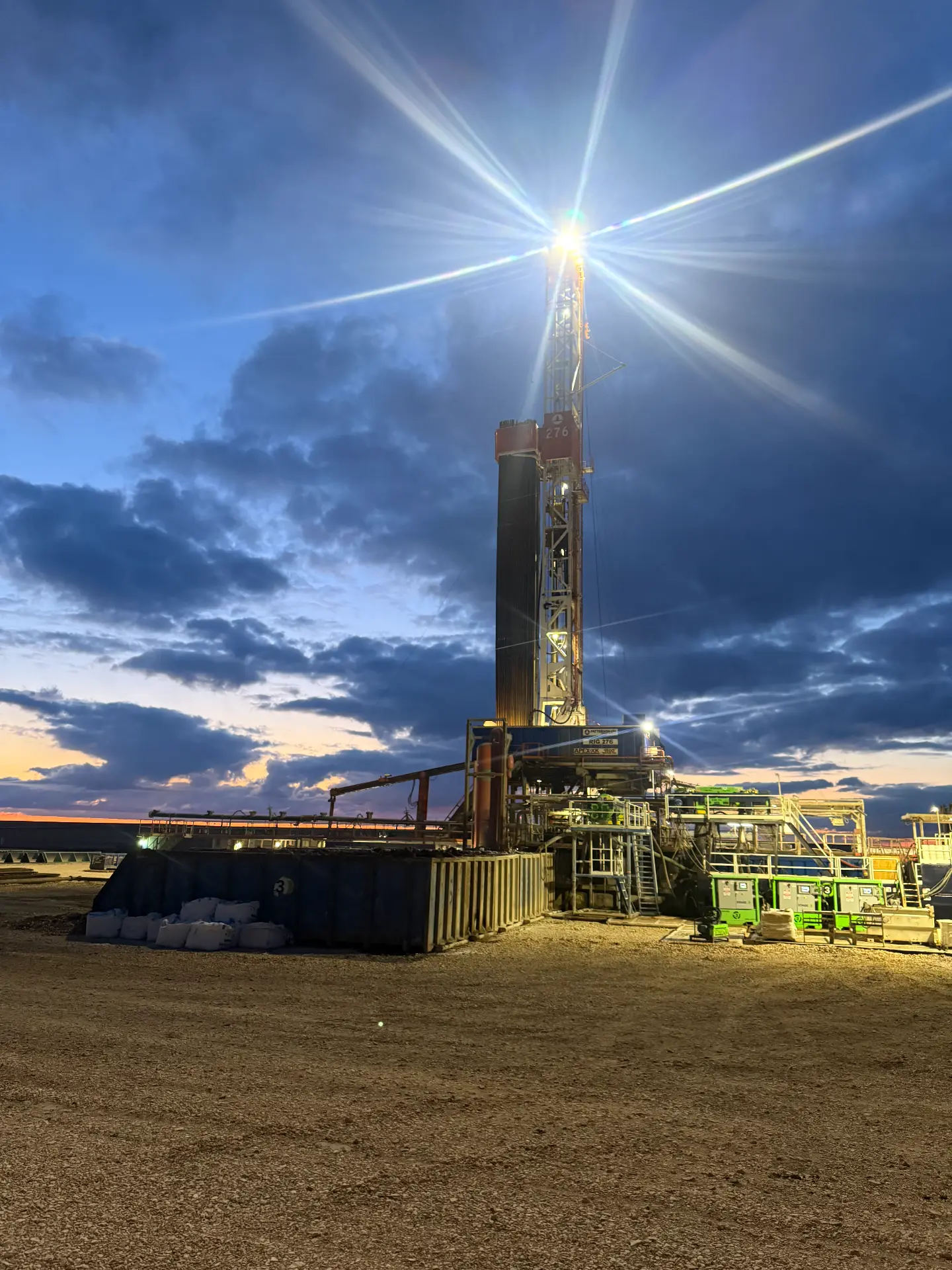 Drilling rig lit up at sunset on a Bakken location
