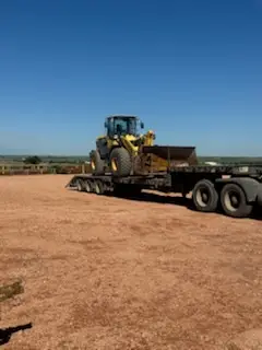 Komatsu wheel loader strapped to a lowboy trailer being hauled across the Bakken