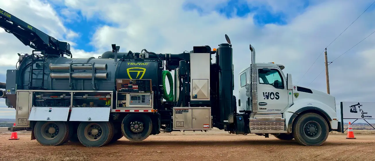 WOS Kenworth TruVac hydrovac truck staged in a Bakken yard with safety cones set