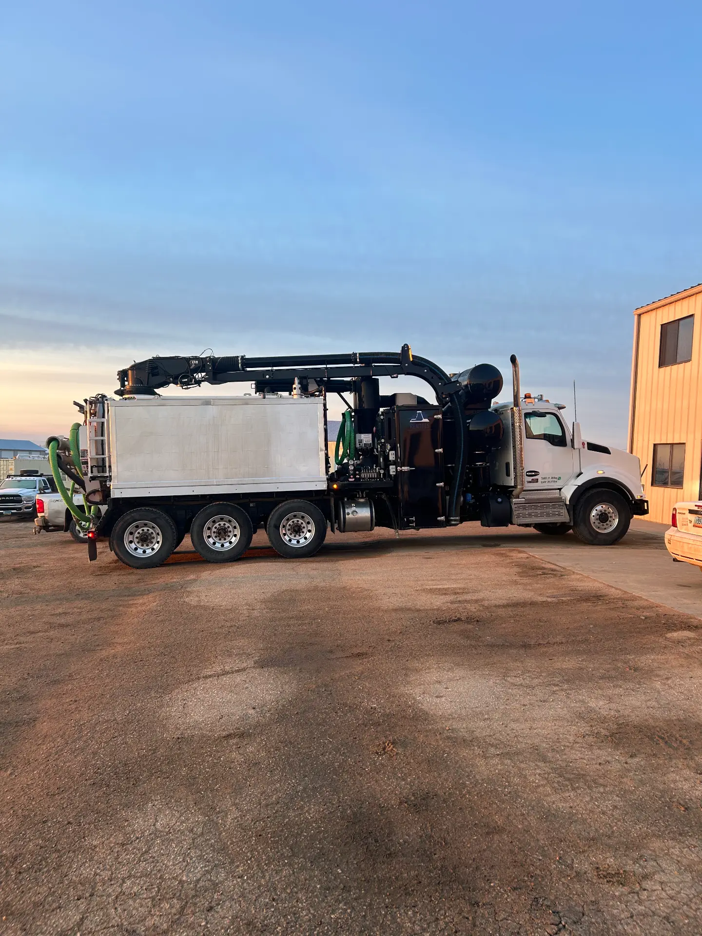 WOS Kenworth tri-axle hydrovac truck parked at the shop at sunset