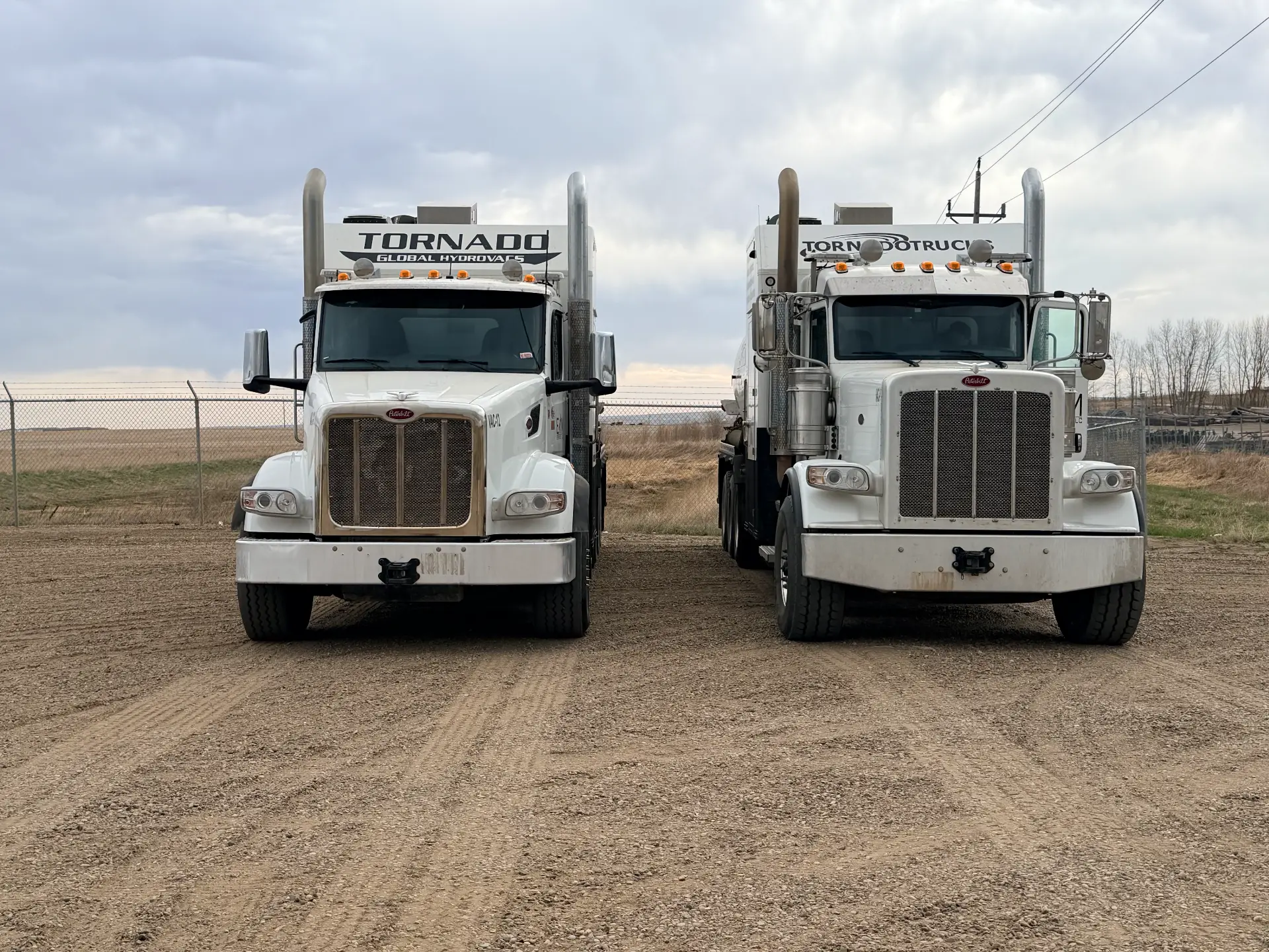 Pair of Tornado Global Hydrovacs Peterbilt trucks parked side by side at a yard