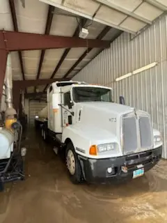 White Kenworth day-cab semi parked inside the WOS heated wash bay for cleaning