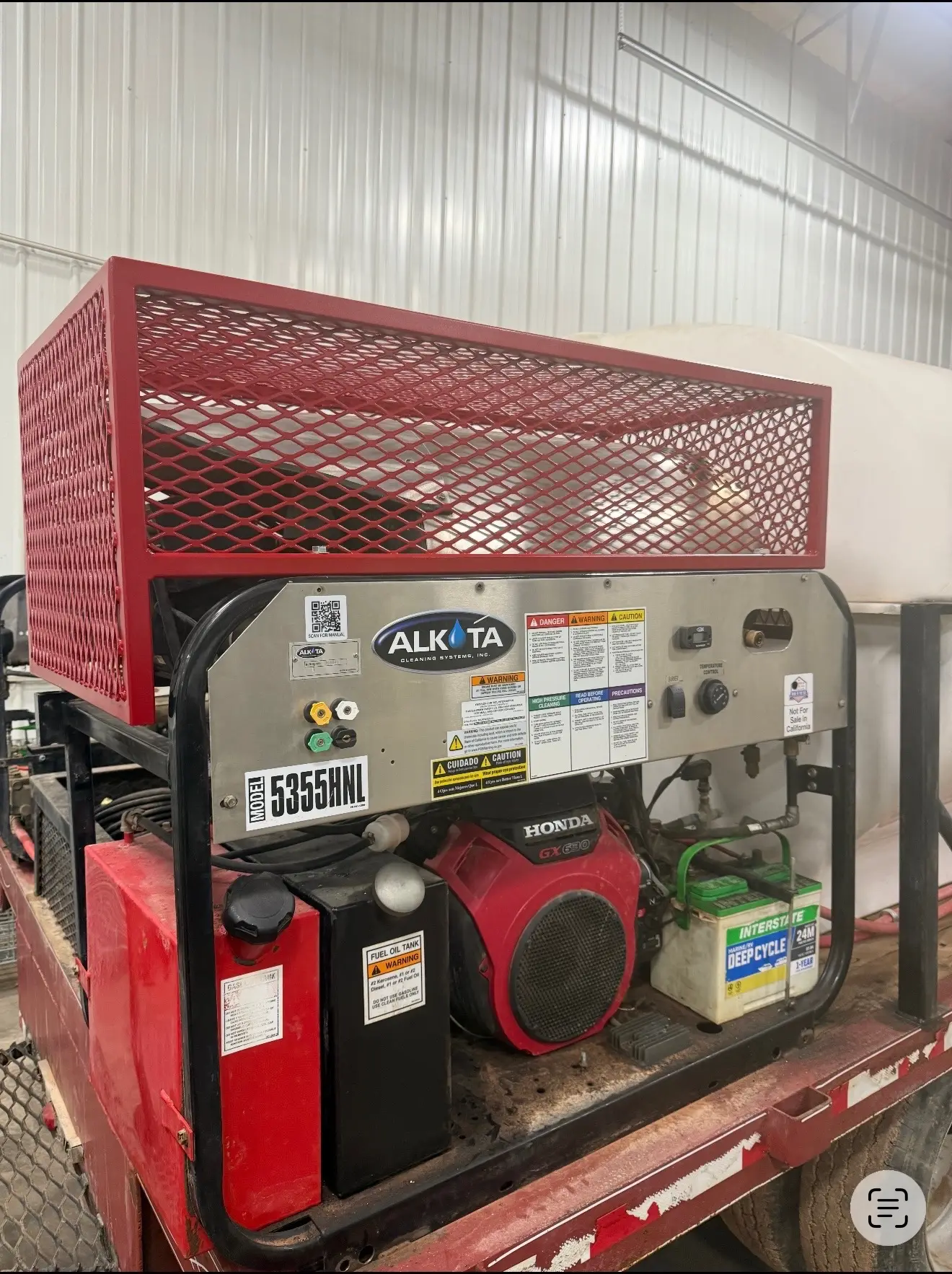 Alkota 5355HNL pressure washer with red guard cage on a WOS skid trailer in the shop