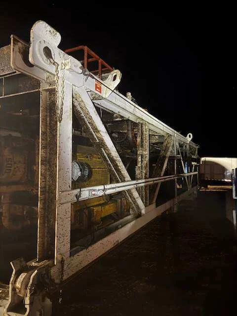 Folded workover mast staged on stands ready for pressure-washing service at night