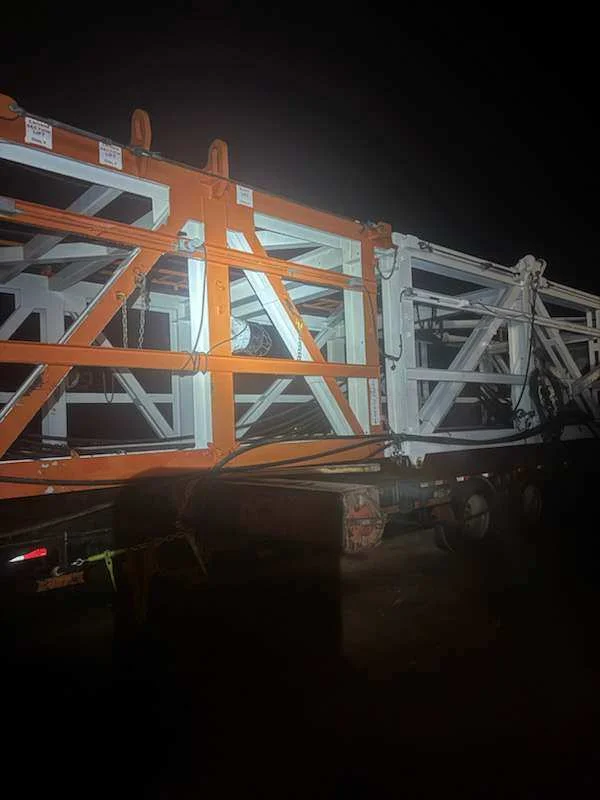 Pressure washed rig section loaded on a trailer at night