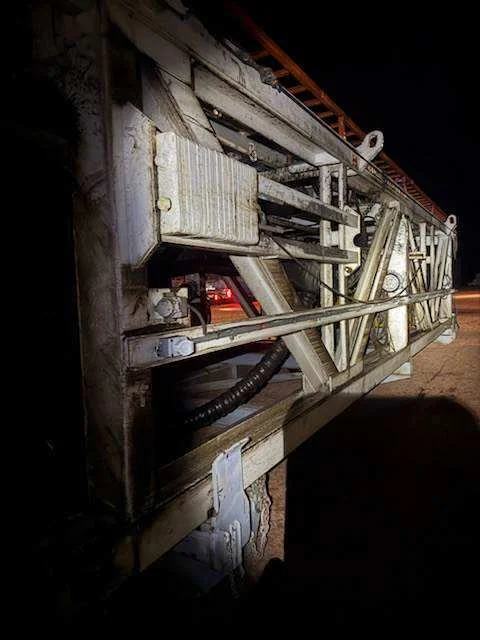 Underside of a folded mast being hot-water cleaned at night in the yard