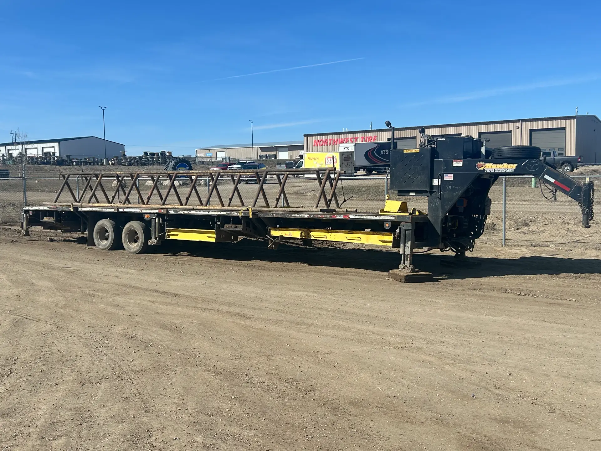 Hawker gooseneck rental flatbed loaded with a stack of pipe rack stands at the WOS yard