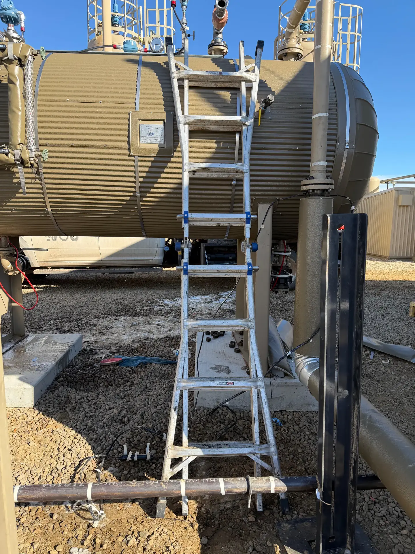 Aluminum ladder leaned against a production tank at a Bakken battery during facility maintenance