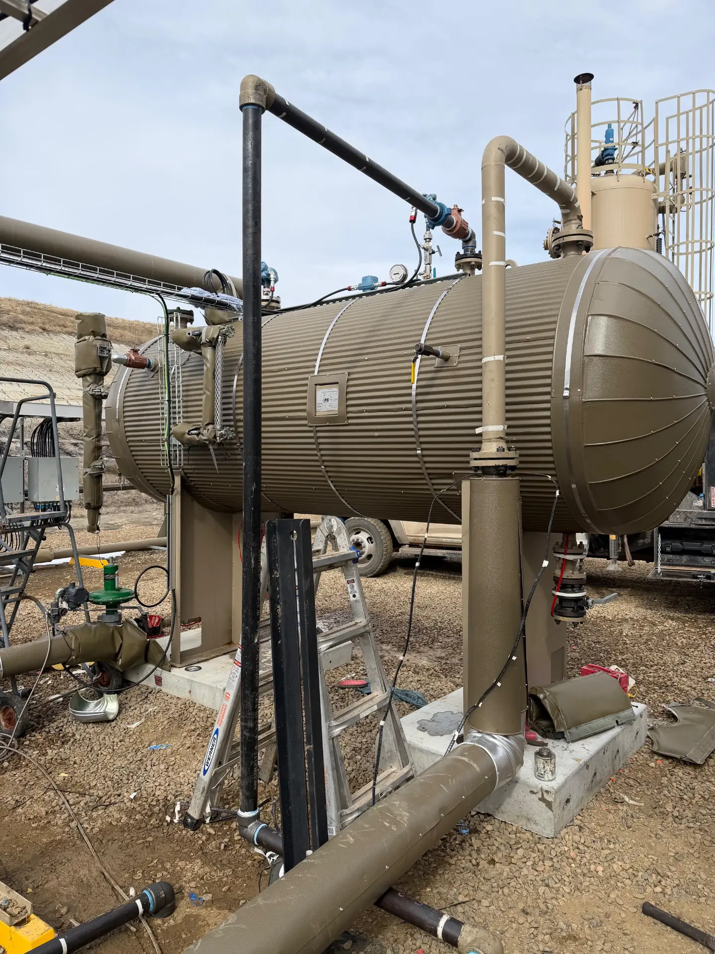 WOS crew servicing a horizontal heater treater vessel and stack at a Bakken production battery