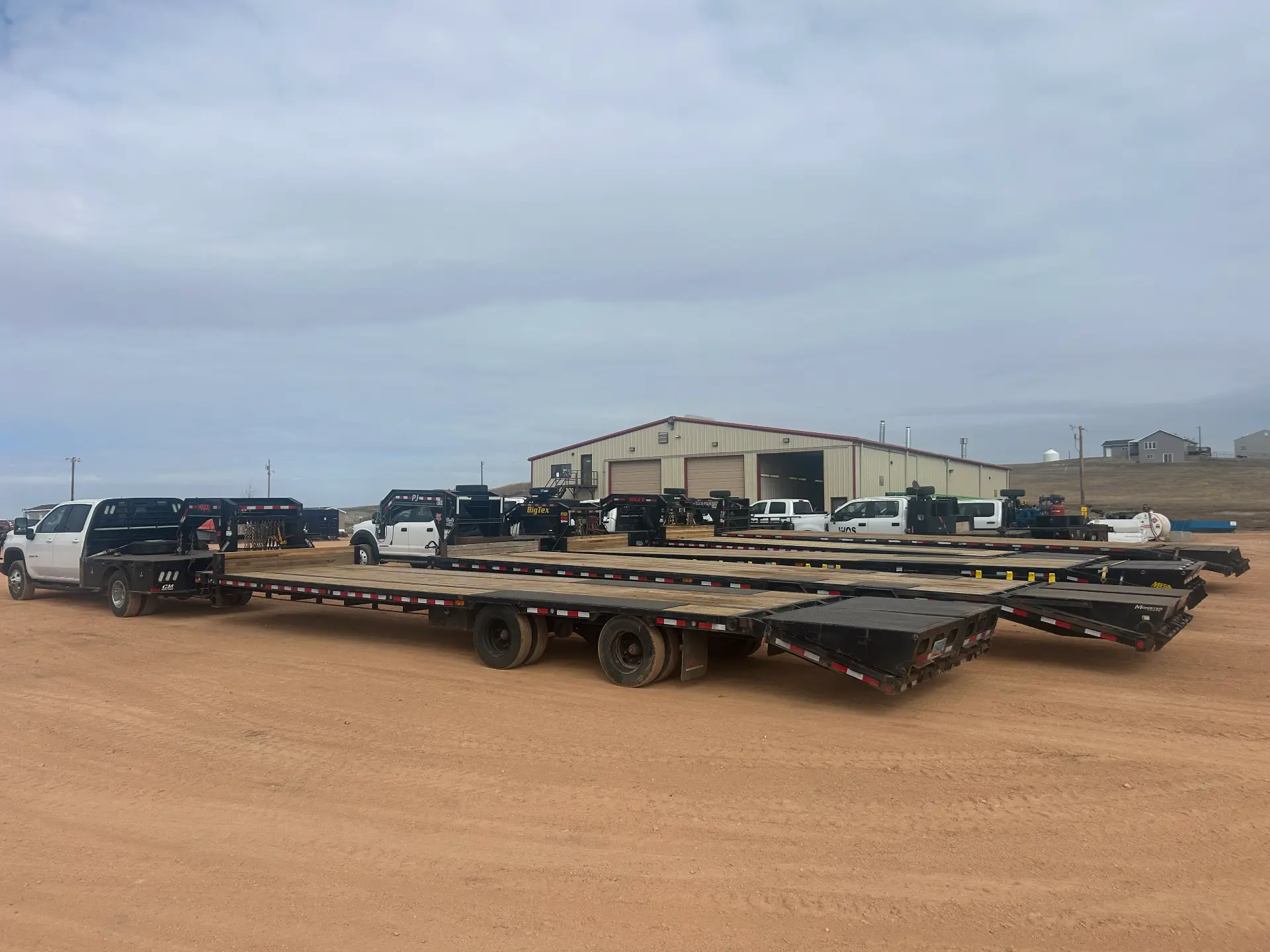 WOS Chevrolet flatbed hooked to a row of gooseneck trailers parked at the WOS shop